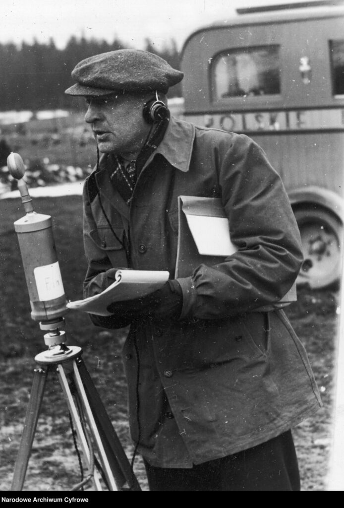 Korespondent radiowy w słuchawkach przed mikrofonem. W tle samochód Polskiego Radia.